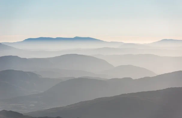 paul-earle-wVjd0eWNqI8-unsplash Peaceful layered hills in a misty landscape.