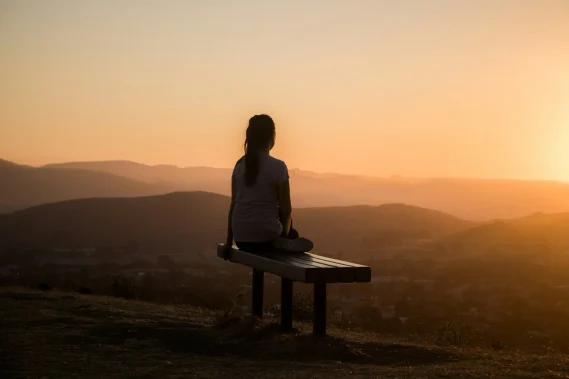 sage-friedman-HS5CLnQbCOc-unsplash (1) Person sitting peacefully overlooking the hills at sunset.
